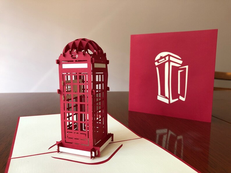 May include: A red 3D pop-up card featuring a detailed model of a classic British red telephone booth. The card is closed, showing a simple silhouette of the telephone booth on the front.