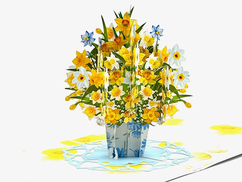 A vibrant 3D pop-up card displaying a bouquet of yellow and white daffodils in a floral-patterned pot. Perfect for special occasions to brighten someone's day