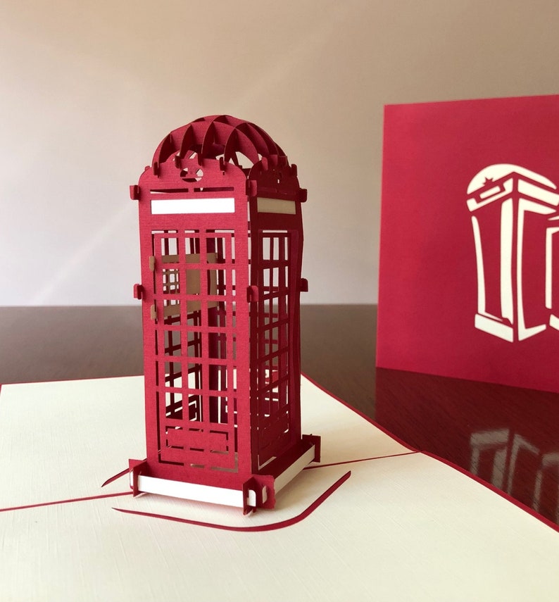 May include: A red 3D pop-up card featuring a detailed model of a classic British red telephone booth. The card is open, revealing the intricate design of the booth.