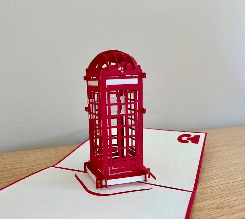 May include: A red 3D pop-up card featuring a detailed model of a classic British red telephone booth.