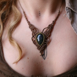May include: A brown macrame necklace with a dark green gemstone pendant.