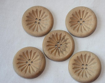 May include: Five wooden buttons with a starburst design and five holes in the center. The buttons are light brown in color and have a smooth, polished finish.
