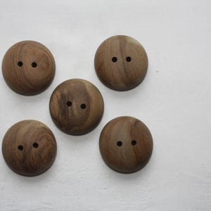 Könnte beinhalten: Fünf Holz-Knöpfe mit jeweils zwei Löchern. Die Knöpfe sind braun mit einer natürlichen Holzmaserung.