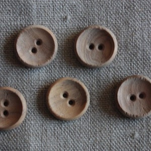 Könnte beinhalten: Sechs Holz-Knöpfe mit jeweils zwei Löchern. Die Knöpfe sind oval geformt und haben eine natürliche Holzfarbe.