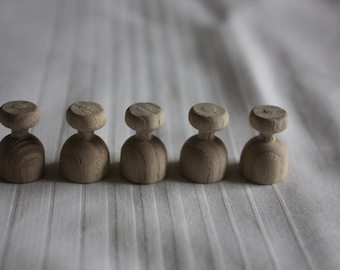May include: Five wooden knobs with a rounded top and a cylindrical base. The knobs are arranged in a row on a white surface.