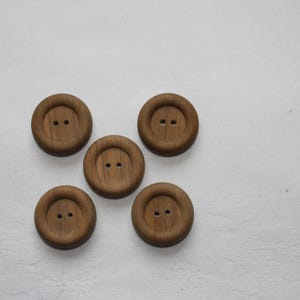 Könnte beinhalten: Fünf braune Holzknöpfe mit jeweils zwei Löchern. Die Knöpfe sind sternförmig auf einem weißen Hintergrund angeordnet.