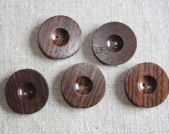 May include: Five brown wooden buttons with two holes each. The buttons have a slightly raised center and a grooved design.