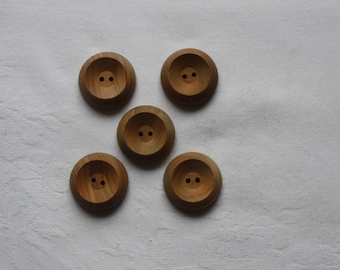 May include: Five wooden buttons with two holes each. The buttons are light brown and have a slightly raised center.
