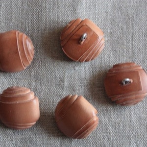 Könnte beinhalten: Fünf braune Holzknöpfe mit geometrischem Muster. Die Knöpfe haben ein Loch in der Mitte zum Nähen.