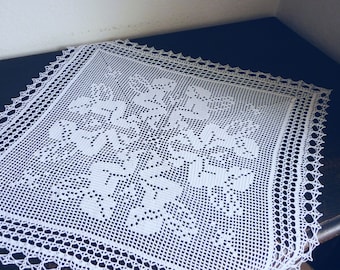 May include: White crocheted doily with a delicate floral pattern. The doily is made of fine thread and has a lacy border.