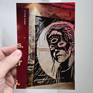 May include: A black and white stencil of a person's face with a third eye on a red, white, and black wall. The stencil is titled "PIPELIED".