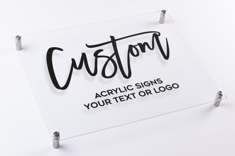 May include: A clear acrylic sign with the word "Custom" written in black script. The sign also includes the text "Acrylic Signs Your Text or Logo".
