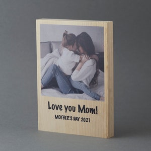 May include: A wooden photo block with a printed image of a mother and child hugging. The text "Love you Mom!" and "Mother's Day 2021" is printed below the image.
