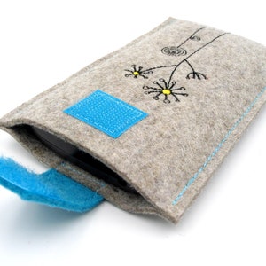 May include: A gray felt phone case with a blue flap and a simple embroidered design of a flower with yellow centers.