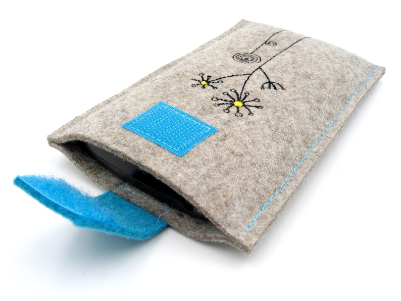 May include: A gray felt phone case with a blue flap and a simple embroidered design of a flower with yellow centers.