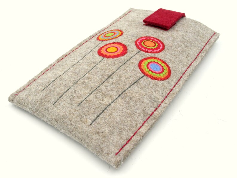 May include: A gray felt phone case with a red flap closure and colorful embroidered flowers. The flowers are red, orange, yellow, green, and blue.