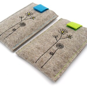 May include: Two gray felt phone cases with a simple black floral design and a contrasting colored flap closure. The case on the left has a blue flap and the case on the right has a green flap.