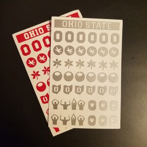 May include: Two sheets of stickers featuring Ohio State University logos and symbols. The stickers are white with gray designs. The top sheet features the words "Ohio State" in white letters. The bottom sheet features the words "Ohio State" in red letters.
