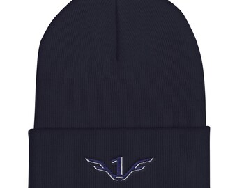 May include: A navy blue beanie with a folded brim. The beanie features an embroidered design of the number "1" with stylized wings in a lighter shade of blue. The hat is made of a soft, knitted material.