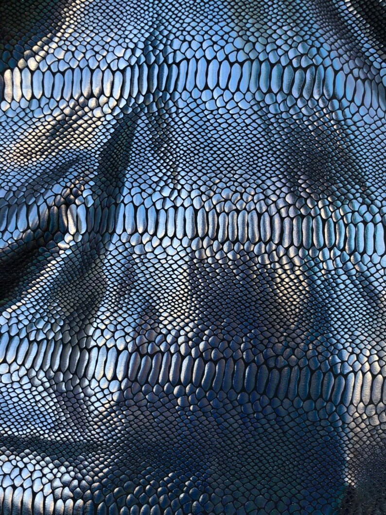 Puede incluir: Primer plano de una tela de piel de serpiente plateada con un patr&oacute;n texturizado y escamoso.