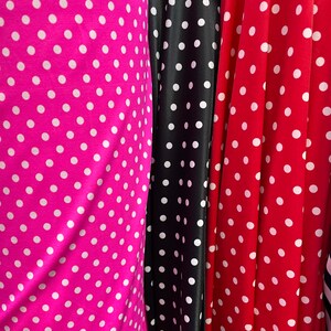 May include: Three fabric swatches with white polka dots on different colored backgrounds. The swatches are pink, black, and red.