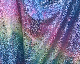 May include: A close-up of iridescent fabric with a textured, cracked pattern. The fabric is a gradient of pink, blue, green, and purple.