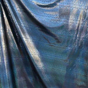 Puede incluir: Primer plano de una tela azul y negra iridiscente con un patr&oacute;n de piel de serpiente.