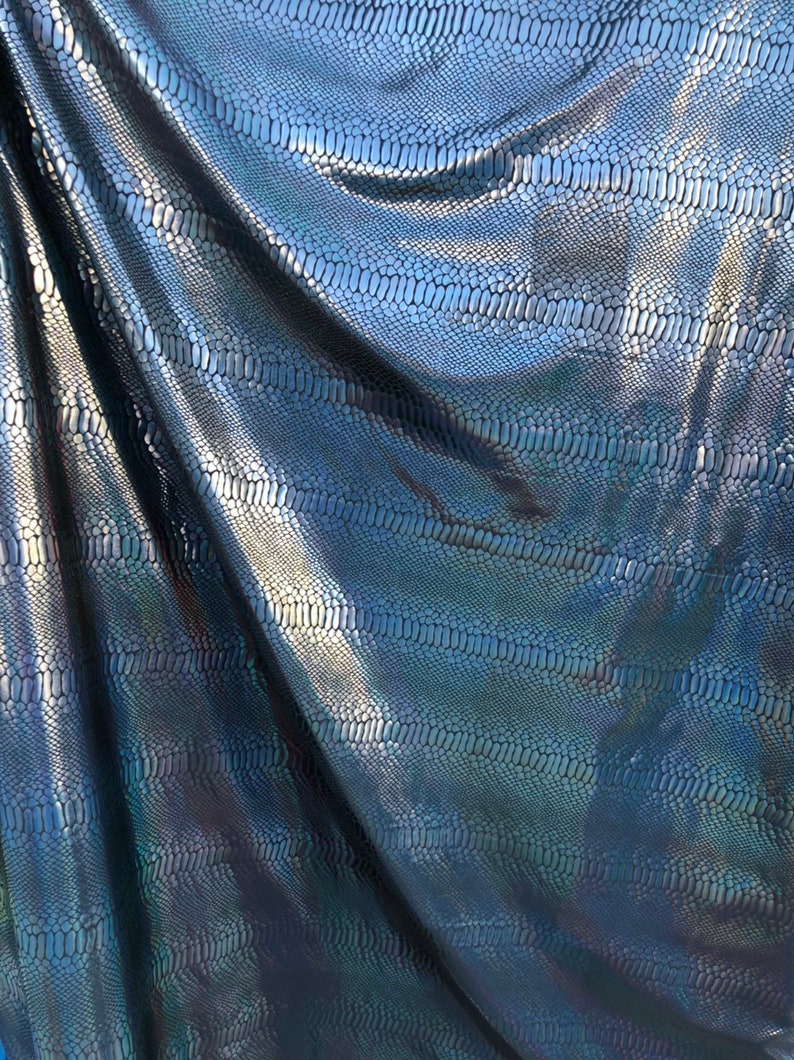 Puede incluir: Primer plano de una tela azul y negra iridiscente con un patr&oacute;n de piel de serpiente.