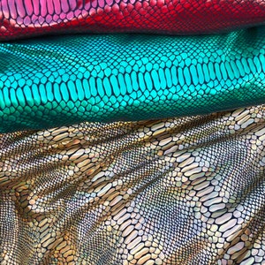Puede incluir: Tres piezas de tela iridiscente con un patr&oacute;n de piel de serpiente. La tela es roja, verde y dorada.
