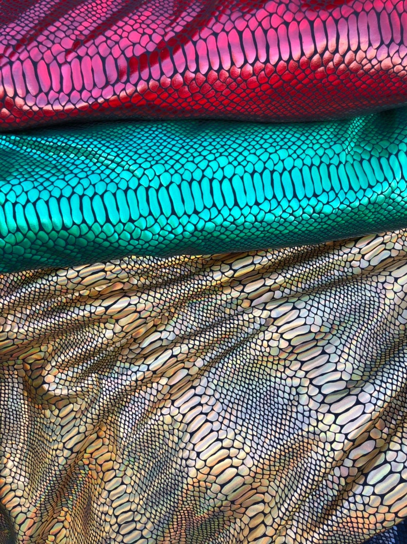 Puede incluir: Tres piezas de tela iridiscente con un patr&oacute;n de piel de serpiente. La tela es roja, verde y dorada.