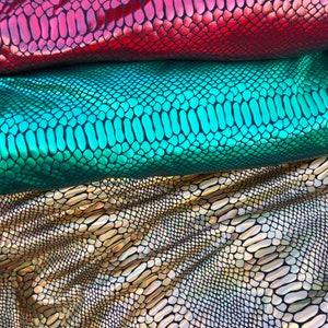 Puede incluir: Tres piezas de tela iridiscente con un patr&oacute;n de piel de serpiente. La tela es roja, verde y dorada.
