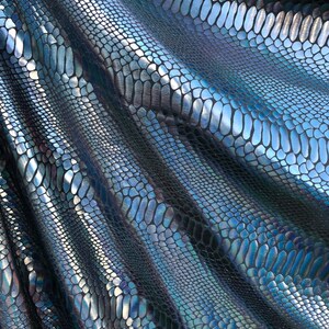 Puede incluir: Primer plano de una tela azul y negra iridiscente con un patr&oacute;n de piel de serpiente.