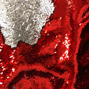 May include: Red and silver reversible sequin fabric. The sequins are small and tightly packed together, creating a shimmering effect.