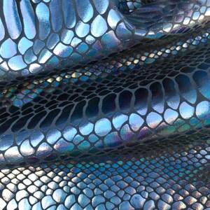 Puede incluir: Primer plano de una tela azul y negra iridiscente con un patr&oacute;n de piel de serpiente.