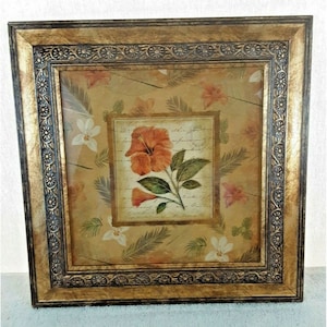 May include: A framed print with a floral design featuring a large orange hibiscus flower with green leaves and white flowers on a beige background. The frame is gold with a dark brown border.