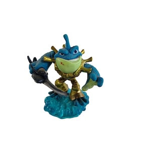 May include: A blue and gold action figure of a frog-like creature with a sword. The figure has a light green belly and a smiling face. It is standing on a blue base.