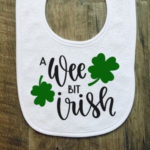 May include: White baby bib with a green shamrock and the text "A wee bit Irish".