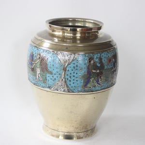 Könnte beinhalten: Eine Vintage-Metallvase mit silbernem Boden und Rand. Der Mittelteil hat einen türkisfarbenen Hintergrund mit einer detaillierten, farbenfrohen Illustration von Figuren. Die Vase hat eine klassische, abgerundete Form.
