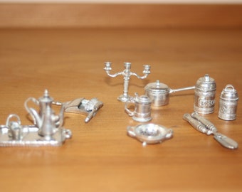 May include: A set of miniature silver-plated kitchenware, including a teapot, a strainer, a candlestick, a small pot, two canisters labeled "Curry" and "Rice", a small tray, and a spatula.
