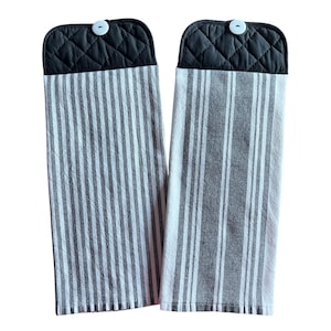 May include: Two black and white striped kitchen towels with black quilted pot holders attached. Each pot holder has a white button.