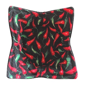 May include: A black quilted bowl liner with a red and green chili pepper pattern. The liner is designed to protect bowls from scratches and heat.
