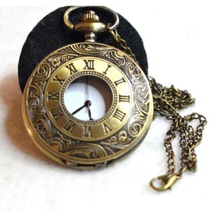 May include: Antique brass pocket watch with Roman numerals on the face. The watch has an ornate, engraved design and a matching chain. The watch is set against a black background.