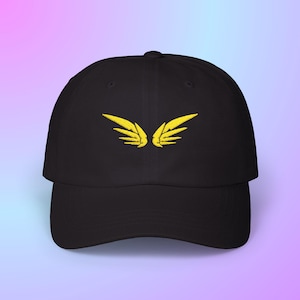 May include: Black baseball cap with a curved brim. The cap features a yellow embroidered wing design on the front. The hat is made of a soft material and has an adjustable strap at the back.