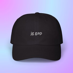 May include: Black baseball cap with a curved brim. The text "jg gap" is printed in white on the front of the cap. The background is a gradient of pink and blue.