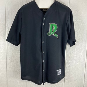 Puede incluir: Camiseta de béisbol negra con un logotipo del equipo verde y blanco en el pecho. La camiseta tiene una parte delantera abotonada y mangas cortas. La camiseta está colgada de una percha blanca.