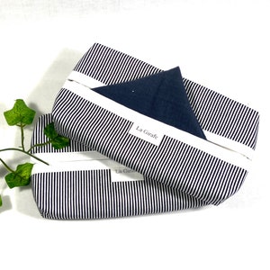 May include: Two black and white striped fabric pouches with white zippers. The top pouch has a dark blue fabric insert and a white label that says "La Girafe".