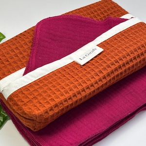 May include: A set of two waffle weave towels, one orange and one pink, with a white label that says "La Girafe".