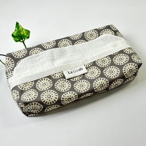 May include: A rectangular tissue box cover with a grey and white floral pattern. The cover has a white opening for tissue dispensing and a label that reads "La Girafe".