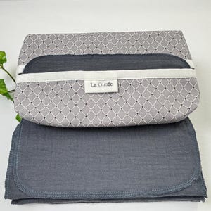 May include: A gray and white patterned fabric pouch with a gray fabric lining. The pouch has a white label with the text "La Girafe" on it.