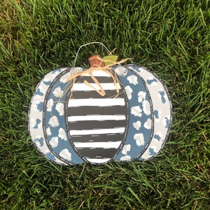 Puede incluir: Un colgador de puerta de calabaza azul y blanco con un patr&oacute;n de rayas blancas y negras y un dise&ntilde;o de estampado de leopardo.